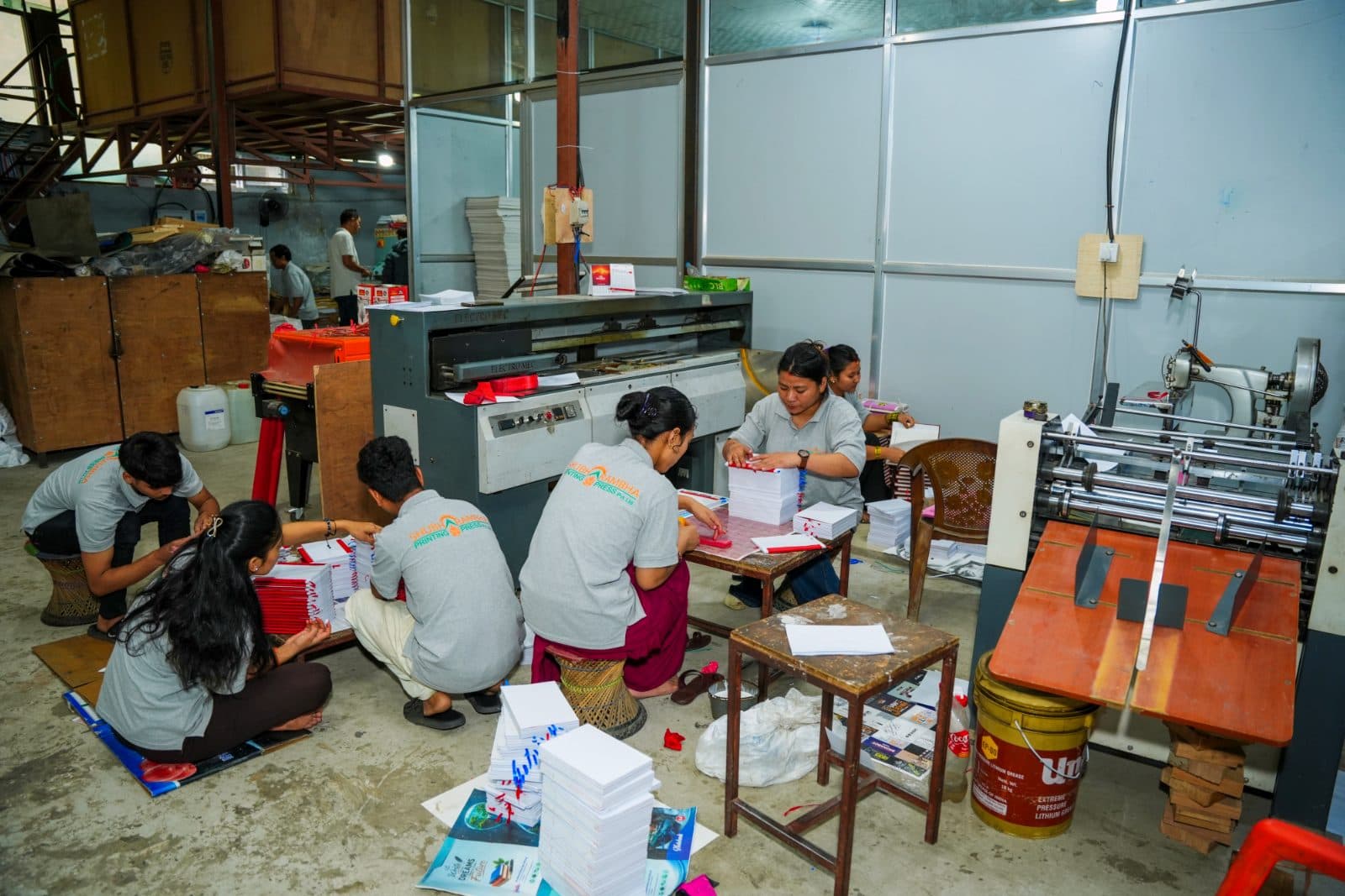 Two of the team hand-finishing and collating freshly bound red books